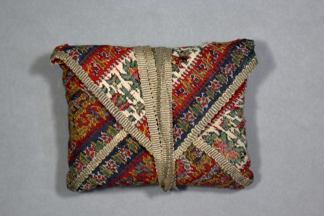 Closed manuscript bag showing the folded construction secured with a textile fastening and the patterned outer fabric